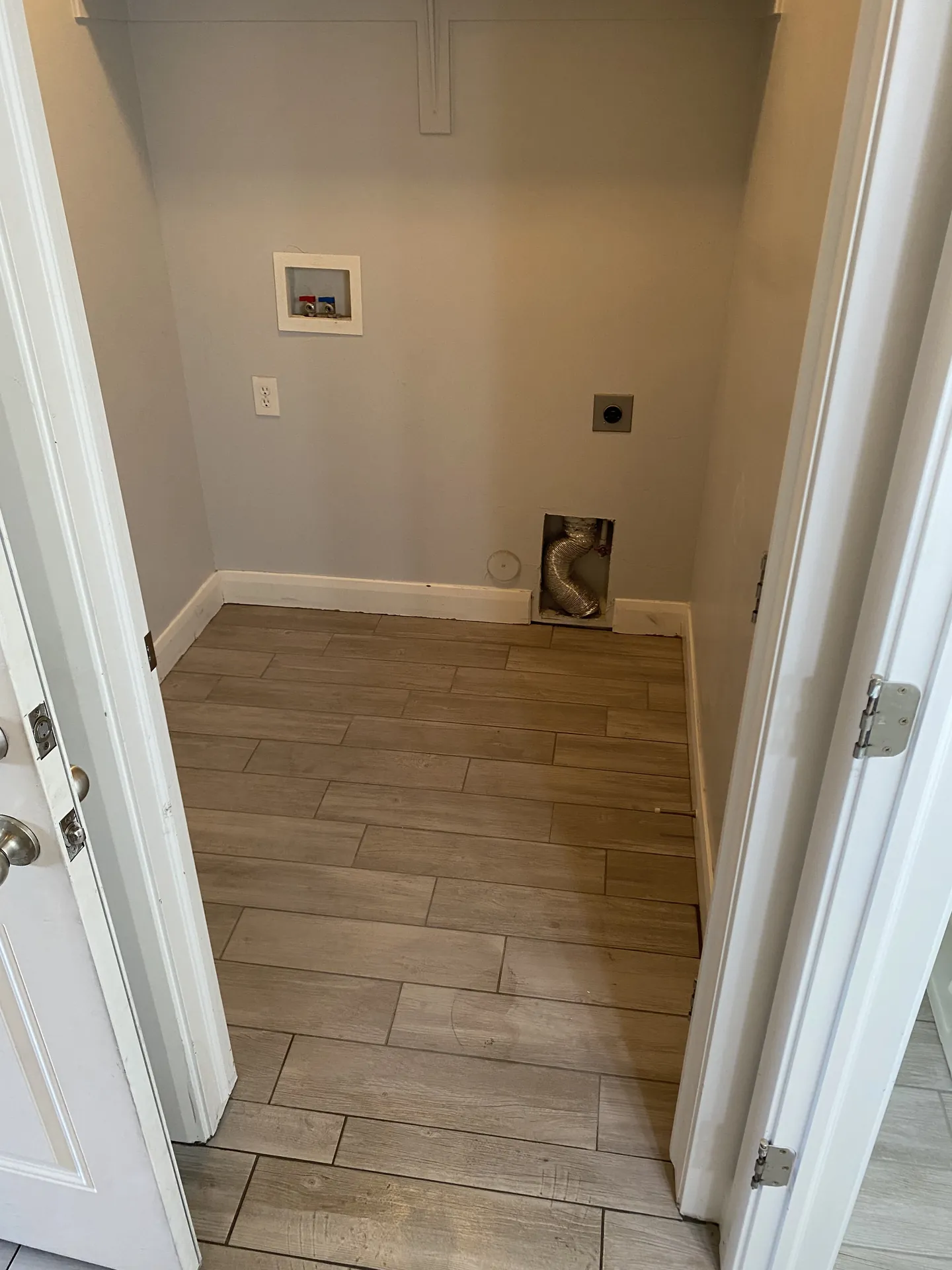 Finished laundry room floor with new wood-look plank tile replacing cracked original tile