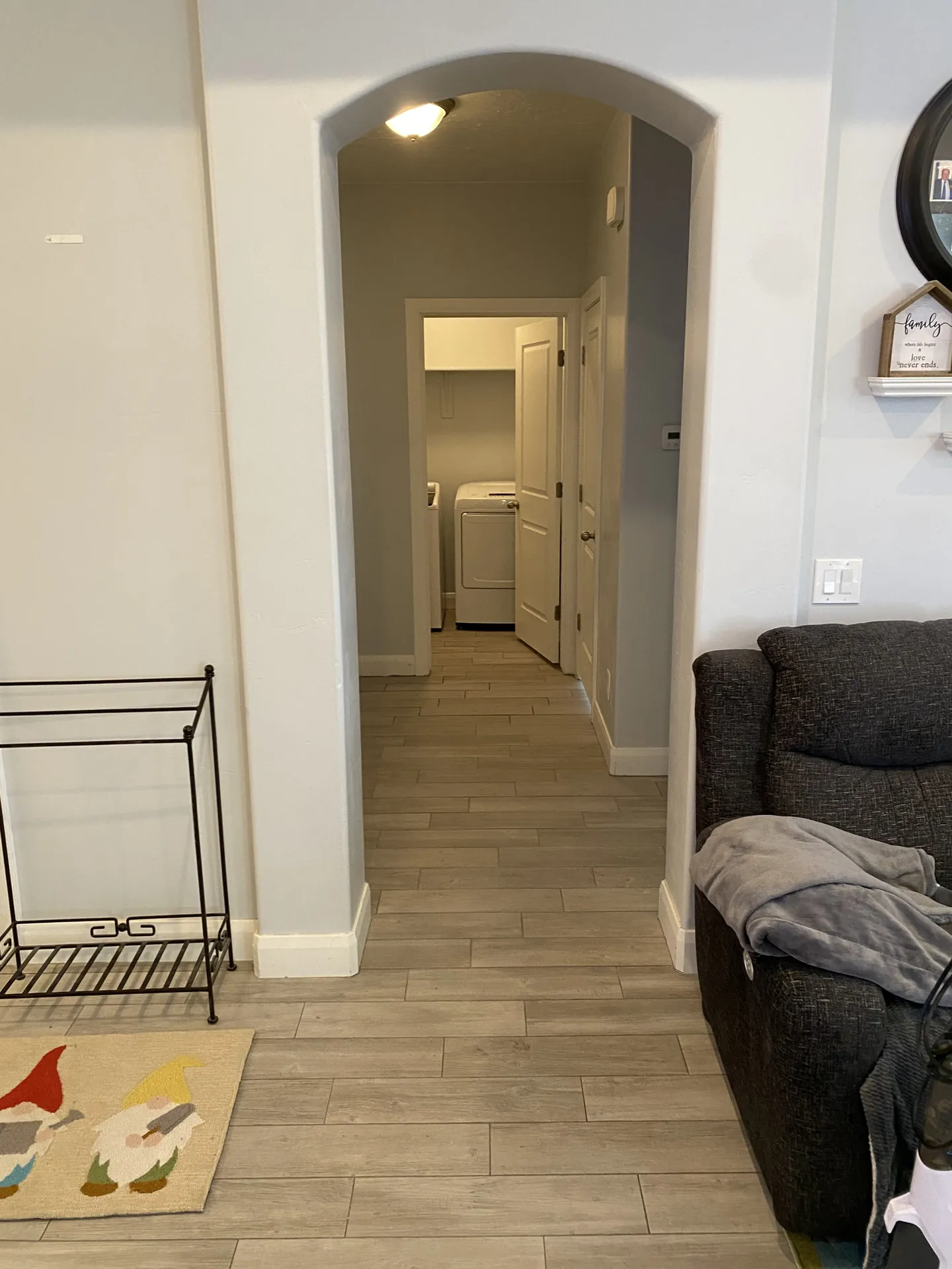 Finished hallway with an arched doorway and new wood-look plank tile continuing through to the laundry room