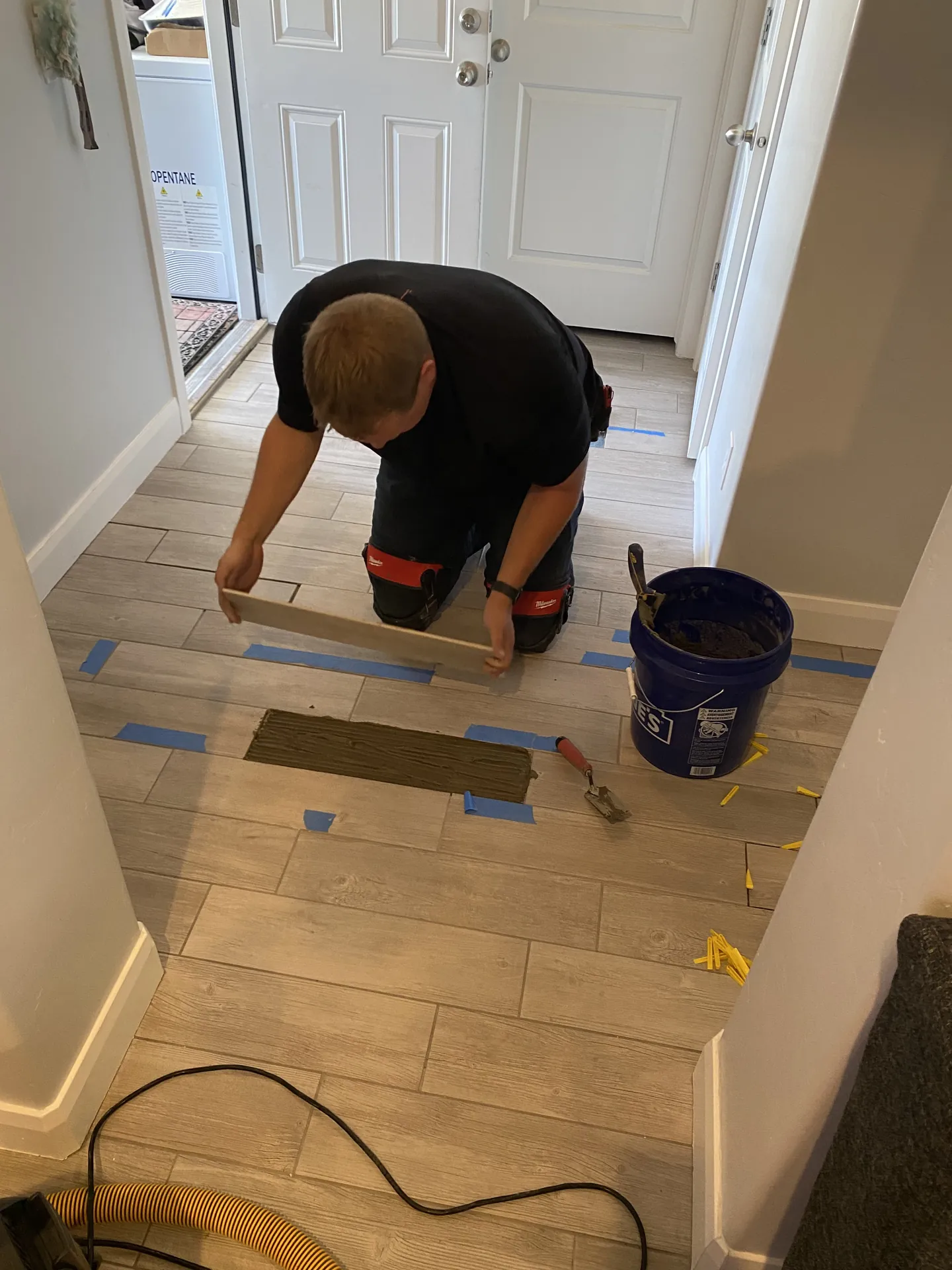 Installer setting wood-look plank tile into thinset mortar with tile spacers in place