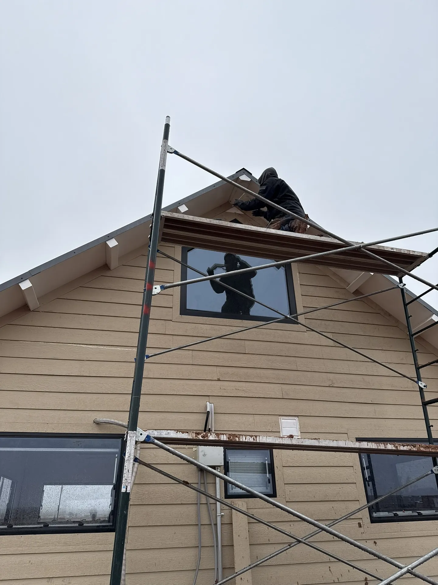 Siding detail work at the gable peak of the Boxabl unit with the loft window trimmed out