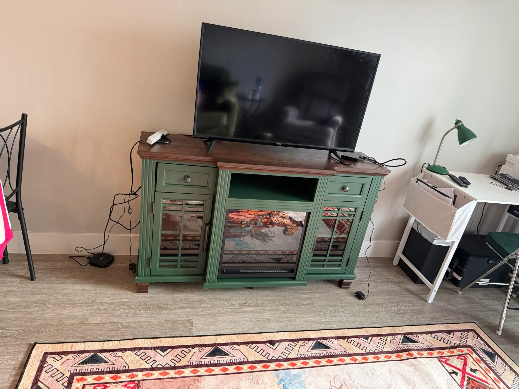 Assembled green TV console with electric fireplace insert running and a TV on top in a Washington, Utah living room